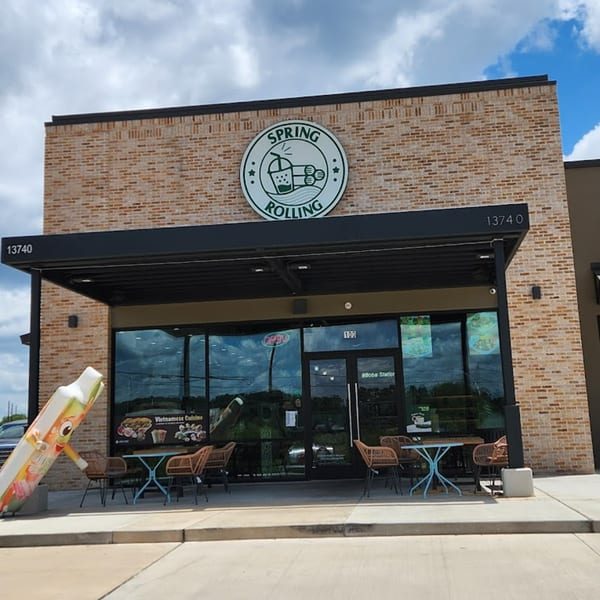 Spring Rolling Vietnamese restaurant exterior with a large logo, outdoor seating, and a giant spring roll mascot.