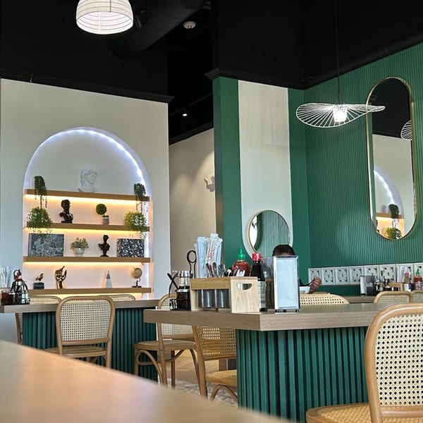 Interior of Spring Rolling, a Vietnamese restaurant, with green and white walls, rattan chairs, and decorative shelves.